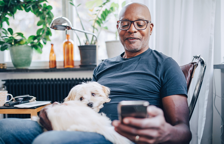 Person sitting in chair with a dog on their lap looking at their phone